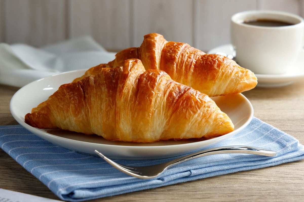 Croissant de mantequilla recién horneado con las capas de hojaldre a la vista