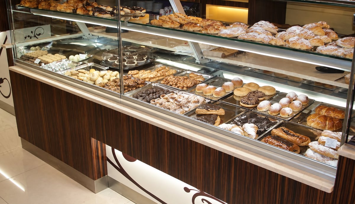 Vitrina del obrador de Esteller con bollería surtida, croissants, hojaldres y dulces espolvoreados